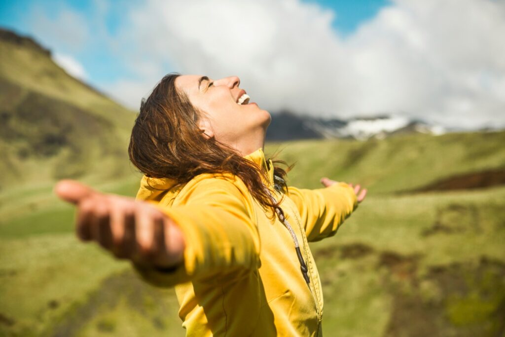 Smiling woman outdoors arms stretched out face turned towards sky