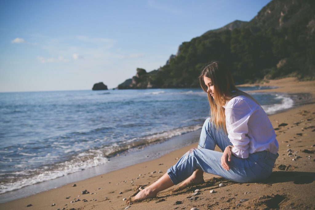 Why mindfulness - Woman sitting on beach with bare feet being mindful