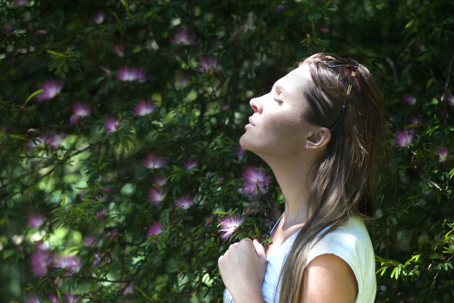 How you can calm your mind - Woman standing with closed eyes outdoors near plant with purple flowers