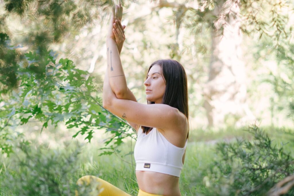 How mindfulness can benefit you physically - Fit woman in sports bra in yoga pose in nature