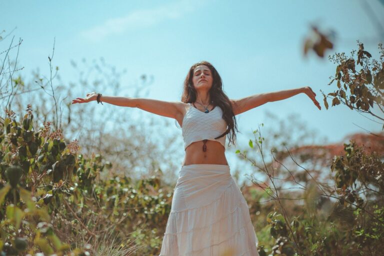 Why is mindfulness so powerful - Woman in white dress with arms stretched out in nature